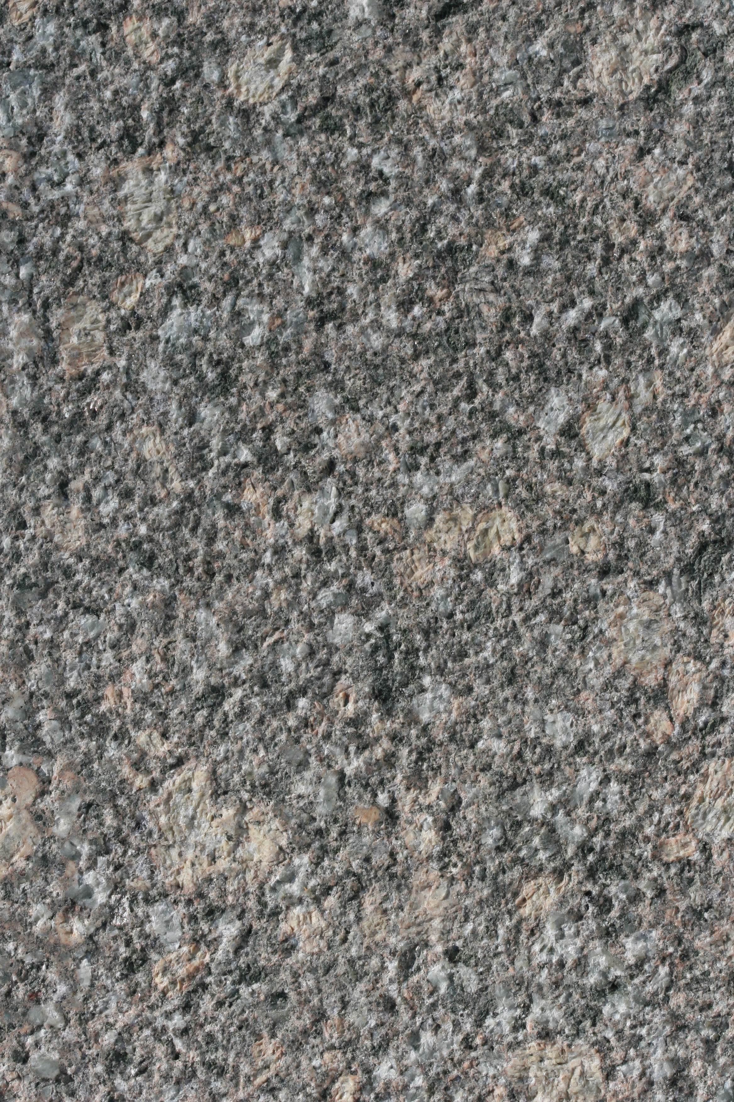 Bush-hammered granite porphyry sample with an evenly pitted surface